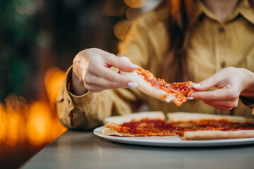 Young pretty woman eating pizza at a bar