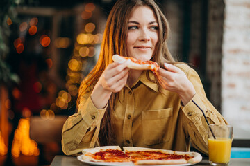 Young pretty woman eating pizza at a bar