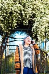 Portrait of a woman using the phone at the park with flowers at the background