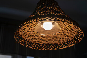 Wooden lampshade on a lamp hanging from the ceiling. Lamp in a dark room