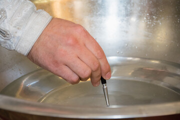 Ukraine, Chernihiv, October 10, 2021: The hand of a priest and water in the font close-up during the baptism of a child in the church