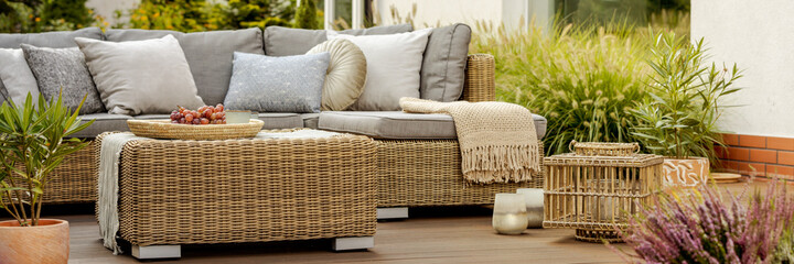 Comfortable wicker garden furniture with grey pillows in beautif