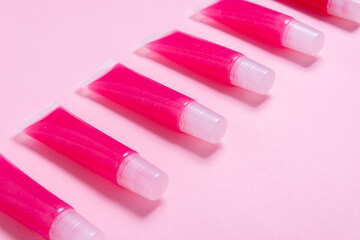 Lot of homemade lip glosses on pink background