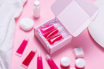 Lot of homemade lip glosses in carton package, mailed on pink background