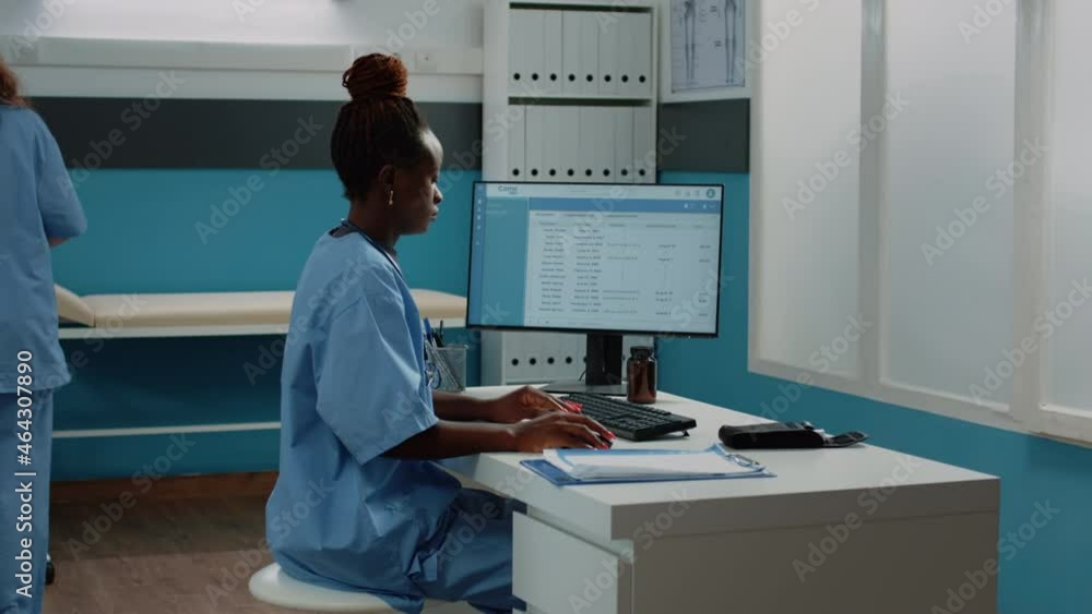 Poster medical assistant typing on computer keyboard in cabinet. woman working as nurse with uniform using 