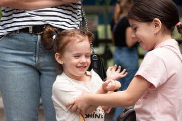 Little girls hugging while playing on the street against the background of their mother