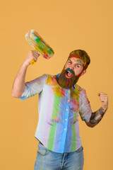 Painter. Handsome bearded painter with paint roller. Room painting job. Repair. Hard hat. Man...