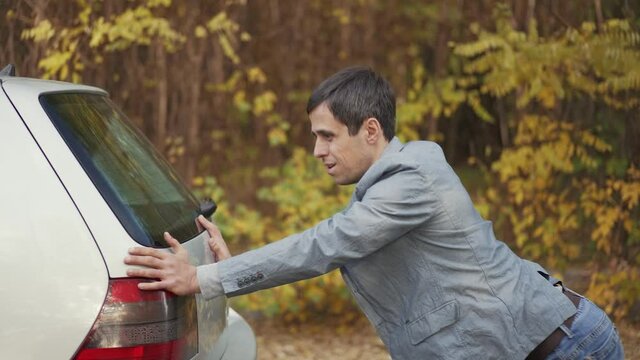 Man pushing a broken car