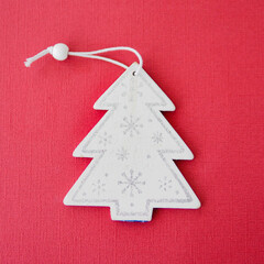 Naklejka na ściany i meble white wooden figurine of a Christmas tree on a red paper background..