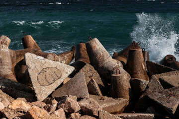 Strengthening the shore from erosion with concrete tetrapods. The seashore with concrete blocks. The element of water. Waves break on concrete.