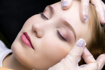 the master erases excess eyebrow styling with a cotton swab from the model's face