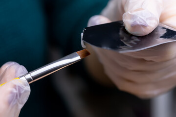 the master squeezes out the composition for laminating eyebrows from the package, on a brush