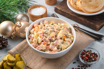 Olivier is a salad of finely chopped vegetables, eggs and sausage on a gray background.