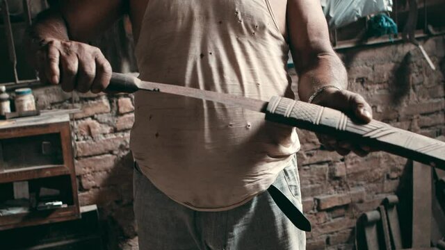 Man slides large kukri knife into a wooden sheath