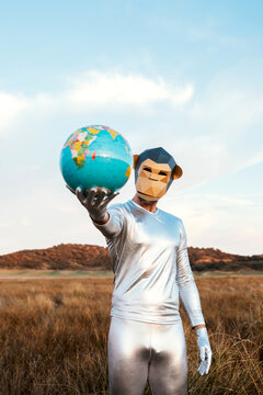 Male with geometric monkey mask giving globe in nature