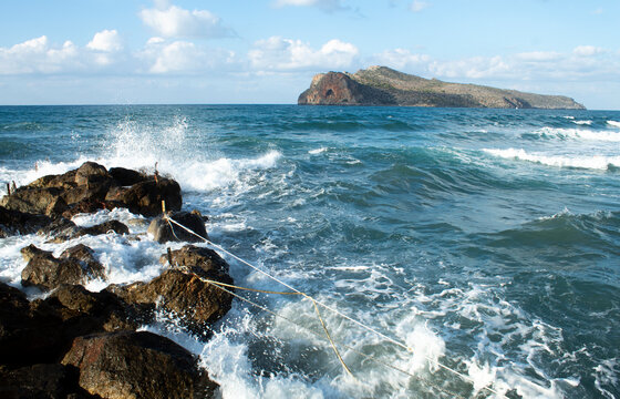 Dramatic seascape at charming Agia Marina village, Crete, Greece. Waves crash on the rocks on a stormy day. Landscape aspect shot with copy space.