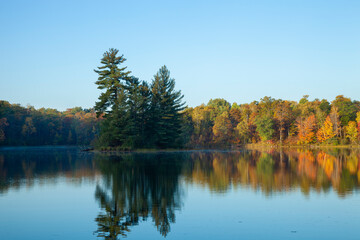 Beautiful calm lake with trees in autumn color and a small island in northern Minnesota at dawn