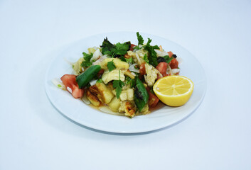 Roasted eggplant served on a white plate, parsley, onion, lemon, tomato, olive oil