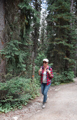 Naklejka na ściany i meble Woman with hiking backpack walking on forest trail