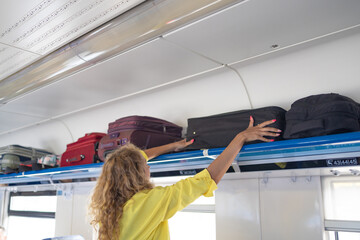 Businesswoman taking bag from luggage compartment in train. Hands take off hand luggage.