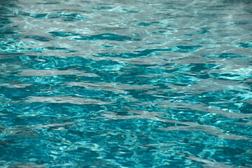 Background of blue water in swimming pool with sun reflection, ripple water wave in pool. Clear water background.