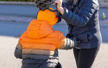 Woman helping child on bicycle with helmet.  Safety and health concept. Sweden. 