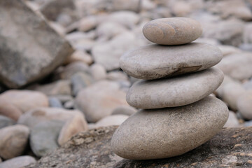 Fototapeta na wymiar Pyramid of four smooth stones on a pebble background. Balance concept. Durance river shoreline, Provence, France.