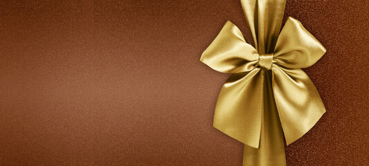 merry christmas gift card with golden satin sparkling ribbon bow isolated on brown glittering background, copy space layout useful for greeting card, label for shopping or sweet chocolate packaging