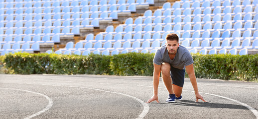 Sporty man in crouch start position at the stadium