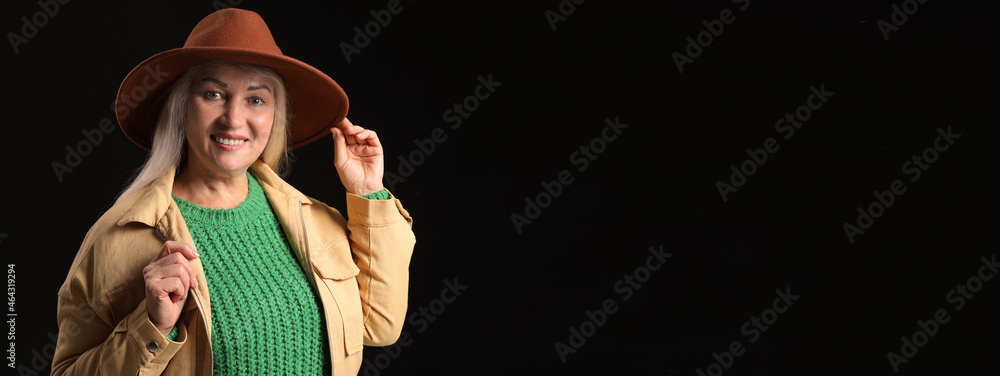 Poster beautiful mature woman in stylish hat on dark background with space for text