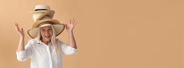 Happy mature woman with stylish straw hats on color background with space for text