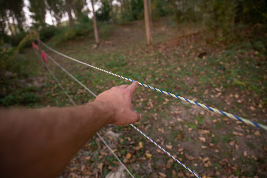 A man's hand touches an electric fence