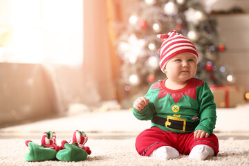 Cute little baby in elf's costume at home on Christmas eve
