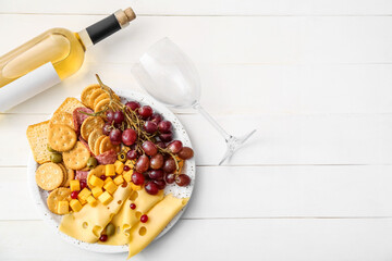 Platter with crunchy crackers and cheese and bottle of wine on white wooden background