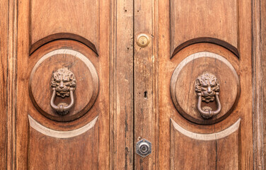 Vintage front door in the medieval city of Italy. Ancient streets of the city, beautiful doors and unusual door handles in the shape of a lion's head.