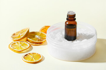 Bottle of essential oil and sea salt in jar on light background
