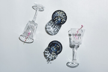 Beautiful empty glasses and flowers on grey background