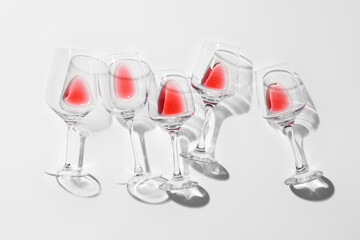 Stylish composition of glasses with leftover red wine on light background