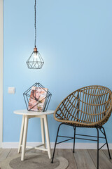 Modern chair and table with magazine near blue wall