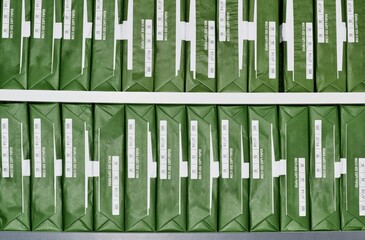 Copy paper reams with generic brand green packaging stacked up in rows on office shelves.