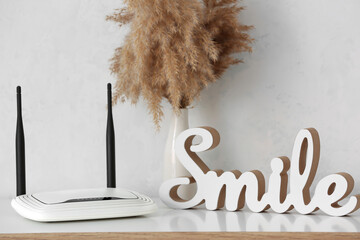 Modern wi-fi router and decor element on table near white wall