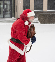 Serious Santa Claus rushes to work in snowy weather