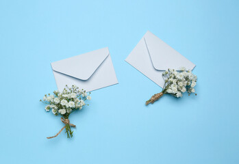 Beautiful gypsophila boutonnieres and letters with wedding invitations on color background