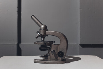 microscope for studying microbes and viruses against a gray three-dimensional wall. concept: photo wallpapers for scientific articles and publications about coronavirus and pandemic.