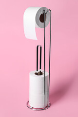 Holder with toilet paper rolls on pink background