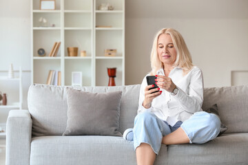 Beautiful mature woman using mobile phone at home