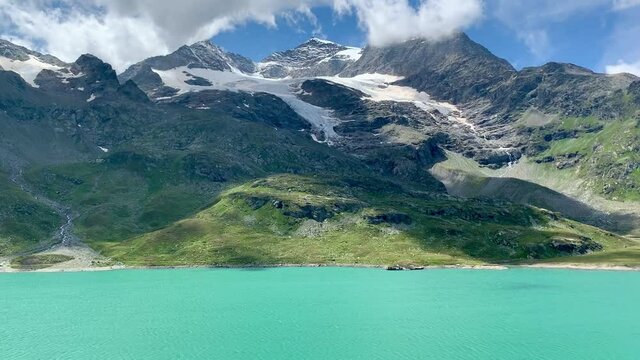 The turquoise Bernina lake with the mountains and the glacier behind in summer in Switzerland
