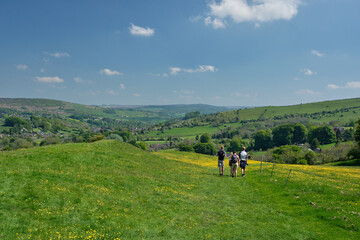 Fototapeta na wymiar Walkers descendng grassy path from Eyam to Stoney Middleton, Hope Valley, Peak District, UK
