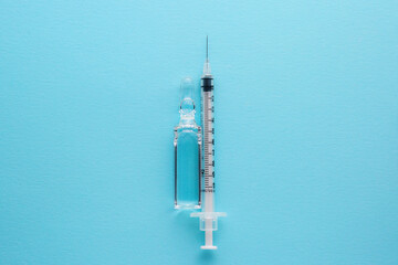 Vaccine with syringe and pills.Vaccine with syringe on a blue background.Vaccine with syringe isolated with place for text.Syringe with ampoule with copy space. Medicine.Treatment.Drugs.means.Vitamins