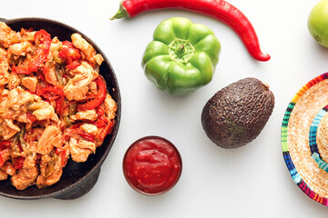 Frying pan with tasty Fajita, sauce and sombrero hat on white background